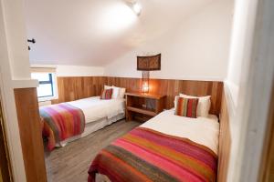 a bedroom with two beds and a table with a lamp at Hotel Aquaterra in Puerto Natales