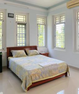 a bed in a white room with windows at Vy Home in Thanh Ðông (1)