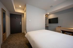 a bedroom with a white bed and a television at Plum Hotel in Osaka
