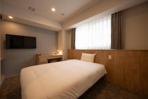 a bedroom with a large white bed and a window at Plum Hotel in Osaka