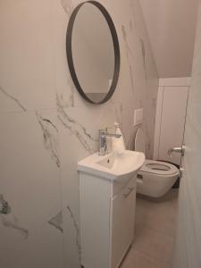 a white bathroom with a sink and a mirror at Apartman Tea in Pićan +6 photos