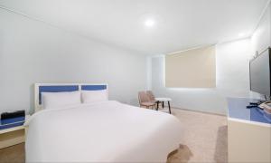 a white bedroom with a bed and a chair at Taean Manripo Feel Hotel in Taean