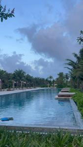 a large swimming pool with blue water and palm trees at Perolas Homestay in Xóm Chum Găng