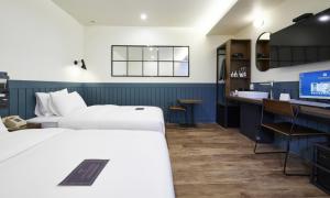 a hotel room with two beds and a desk with a computer at JustSleep Namyangju Dasan in Namyangju