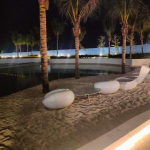 a row of white benches on a beach with palm trees at Azure North MiCasa in San Fernando