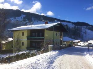 ein gelbes Gebäude im Schnee mit einem Berg in der Unterkunft Appartement Haus Seer in Wagrain