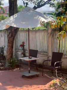 a table with an umbrella next to two chairs at Vy Home in Thanh Ðông (1)