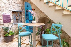 a table and chairs in front of a building with a blue door at El Khan Guesthouse & Art - A Complex of 4 Middle Eastern-Style Suites in Nazareth