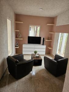 a living room with two chairs and a flat screen tv at CABAÑAS SANAMBO fraccionamiento los gallos in Balastre Rojo