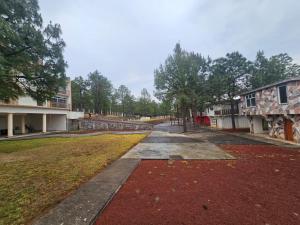 a walkway through a yard with a building and trees at CABAÑAS SANAMBO fraccionamiento los gallos in Balastre Rojo +5 photos