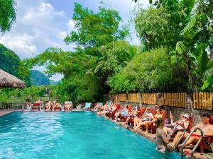 a group of people sitting in chairs by a swimming pool at Tam Coc Central Backpacker Hostel in Vũ Lâm