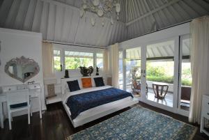 a bedroom with a bed and a desk and windows at Villa Pantai Matanai in Tianyar +61 photos