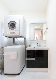 a white kitchen with a microwave and a sink at HIRO HOUSE Marugame - 丸亀駅徒歩5分 in Marugame