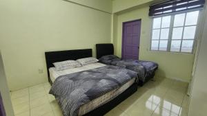 two beds in a bedroom with a purple door at The Gladiator Homstay in Brinchang