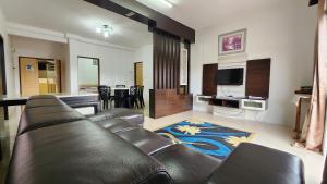 a living room with a leather couch and a television at The Gladiator Homstay in Brinchang