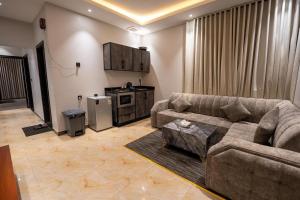 a living room with a couch and a kitchen at راحتي هنا للشقق المخدومة in Riyadh