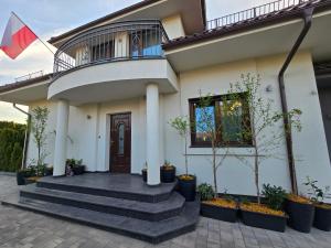 a white house with a balcony and stairs at Szary odpoczynek na piętrze - wieś Pogórze, dla zmotoryzowanych in Pogórze