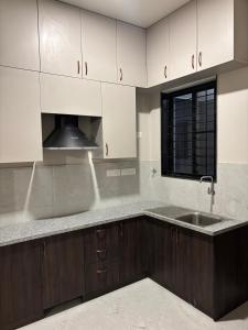 a kitchen with white cabinets and a sink and a window at Md Couple Stay in Covelong