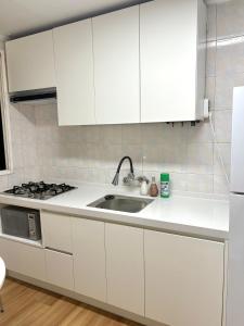 a kitchen with white cabinets and a sink at Herry Stay in Seoul