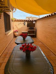 a patio with two tables with red flowers on it at Casa Rural La Libélula Azul in Polán
