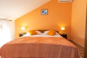 a bedroom with a bed with orange walls and two lamps at Apartments Diana in Luka