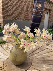 a vase with flowers on a table in front of a sign at Maison Lion Luxe gastenverblijf in Borgloon