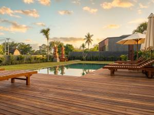 a wooden deck with benches next to a swimming pool at Frontera Nyanyi in Tabanan