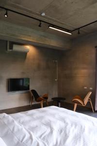a bedroom with two chairs and a bed and a tv at Tao Ye BnB in Miaoli