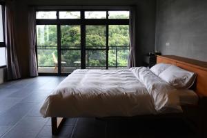 a bedroom with a large bed and a large window at Tao Ye BnB in Miaoli