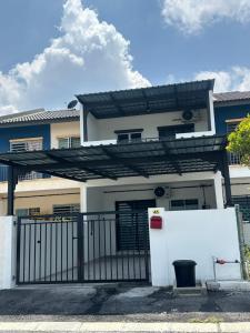 a white house with a black gate and a building at Khaeel Homestay in Ipoh