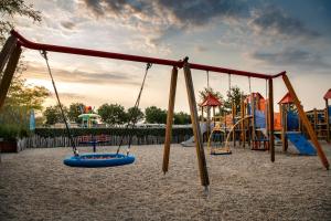 a playground with swings and slides in the sand at Siblu Duinzicht in Koudekerke