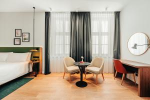 a hotel room with a bed and a desk and chairs at Hilton Garden Inn Radom in Radom +74 photos