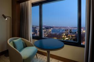 a room with a table and a chair and a large window at Doubletree By Hilton Istanbul Macka in Istanbul