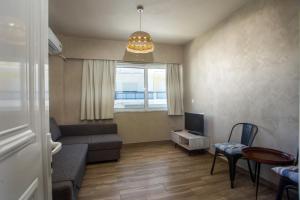 a living room with a couch and a tv and a window at Atma Beach Rooms & Suites in Faliraki