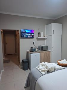 a bedroom with a bed and a kitchen with a tv at House Sawubona in Kroonstad