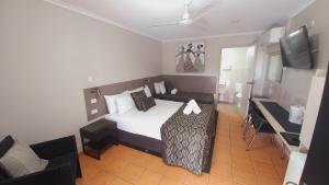 a bedroom with a bed and a desk and a television at Golden Palms Motor Inn in Bundaberg