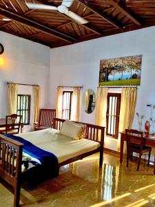 a bedroom with a bed and a table and windows at Cherys Bunglow Homestay- Rooms in Thiruvalla