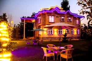 a house with purple lights and tables and chairs at Amberwoodinn in Munglor
