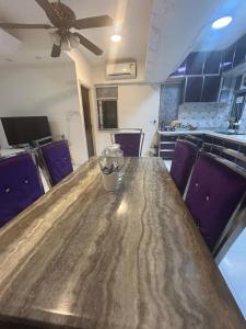 a large wooden table in a kitchen with purple chairs at 2 bhk flat available in tst in Hong Kong +5 photos