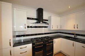 a kitchen with a black stove and white cabinets at Ocean House - Weymouth in Weymouth