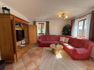 a living room with a red couch and a tv at Ferienwohnungen Am Kirchberg in Neualbenreuth