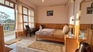 a bedroom with a bed and a desk and a window at Red Cherry Homestay, Nokdara in Lava