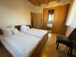 a bedroom with a bed with white sheets and a chair at Ferienwohnungen Am Kirchberg in Neualbenreuth