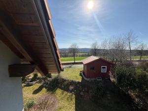 a view of a small red house in a field at Ferienwohnungen Am Kirchberg in Neualbenreuth