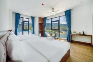 a bedroom with a large white bed and large windows at Vinh Hy Horizon in Vĩnh Hy