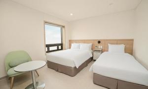 a hotel room with two beds and a chair at Staz Hotel Heritage in Jeju +64 photos