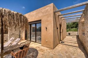 a patio with a couch and chairs on a stone building at Olive Luxury Suites - ADULTS ONLY in Kamilari