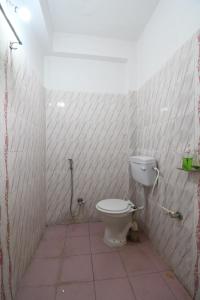 a bathroom with a toilet in a white tiled wall at Hotel Sonnet Inns in Rānchī +1 photo