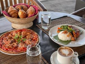 a table with plates of food and a bowl of bread at BougainVilla - Oceanfront villa with Cook, ideal for Weddings and Events in Keramas