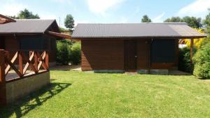 a wooden house with a grass yard in front of it at Lican Ray Cabañas Los Primos in Licán Ray